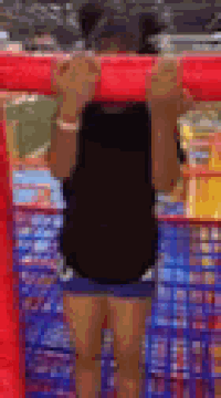 a little girl is hanging upside down on a red bar .