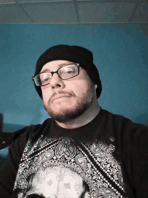 a man with glasses and a beard wears a black bandana