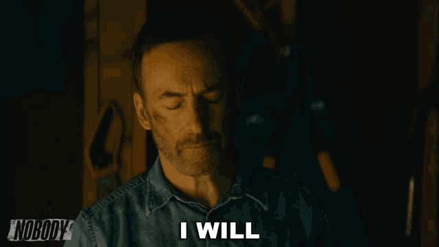 a man in a denim shirt says i will in a dark room