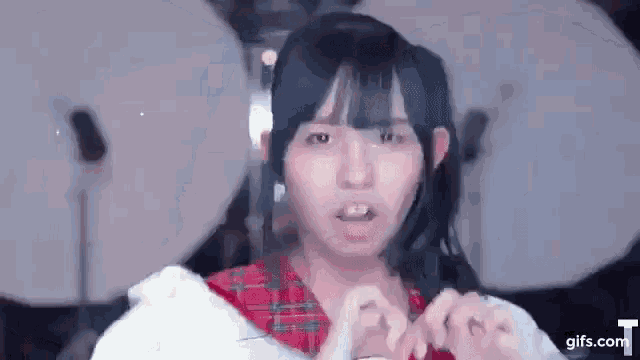 a young girl with pigtails is making a funny face while wearing a plaid shirt .