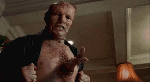 a man with a huge hole in his chest is holding his shirt up .