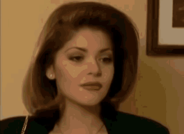 a close up of a woman 's face with a picture on the wall behind her