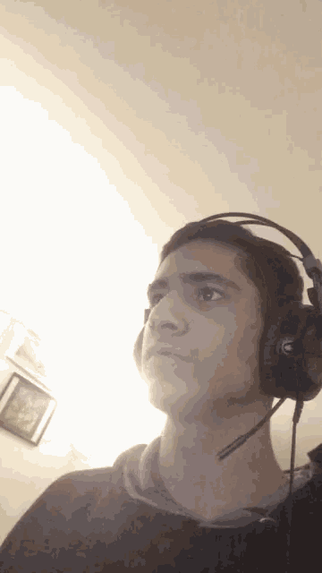 a young man wearing headphones and a microphone looks at the camera
