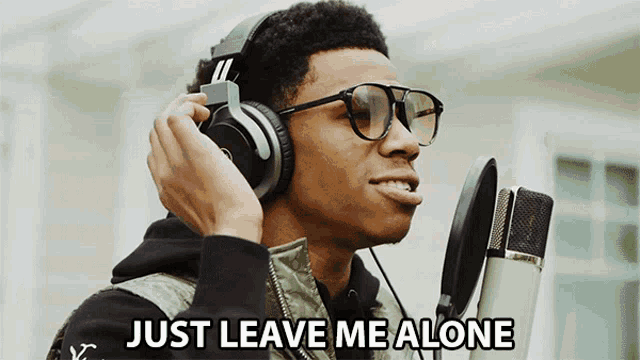 a man wearing headphones and glasses is singing into a microphone with the words just leave me alone written below him