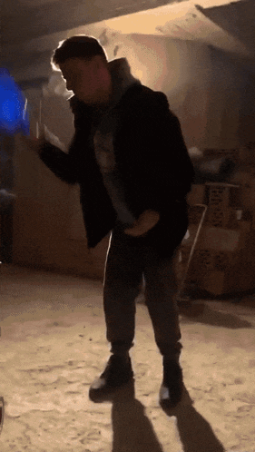 a man is dancing in a dark room with boxes stacked on the floor