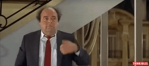 a man in a suit and tie is standing in front of stairs .