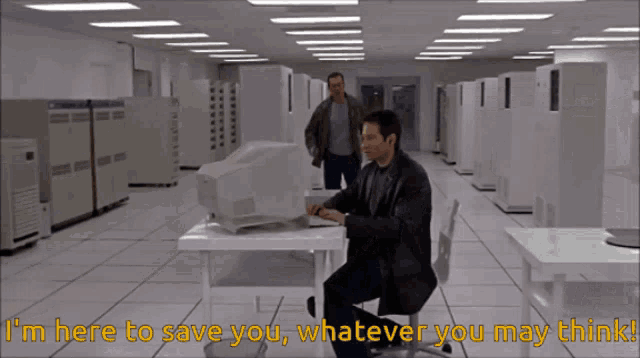 a man is sitting at a desk with a computer and the words i 'm here to save you whatever you may think