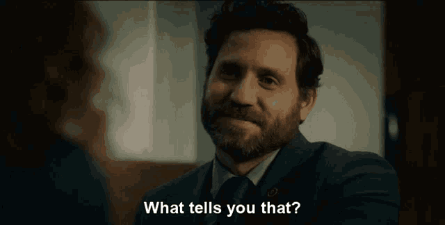 a man in a suit and tie is talking to a woman and says " what tells you that "
