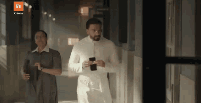 a man and a woman walking down a hallway with a xiaomi logo on the bottom