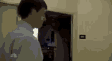 a man in a blue shirt is standing in a room with a door open .