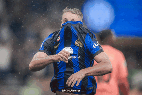 a soccer player covering his face with his shirt which says bundes on it
