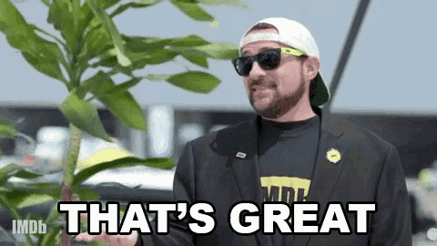 a man wearing sunglasses and a hat is holding a plant and saying that 's great .