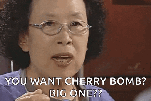 a woman wearing glasses is holding a spoon and saying `` you want cherry bomb big one ? ''