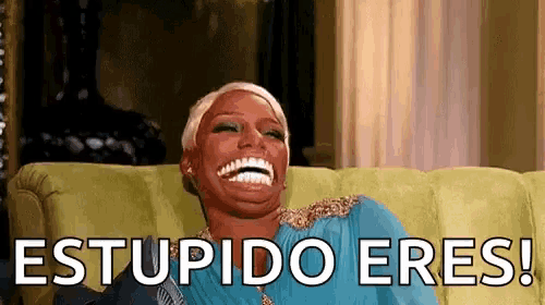 a woman is sitting on a couch and laughing with the words stupido eres written on the bottom of her face .