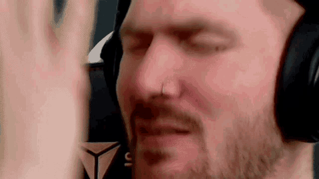 a man with a beard wearing headphones and a nose ring is making a funny face .