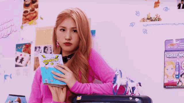a girl in a pink sweater is holding a book that says " water world "