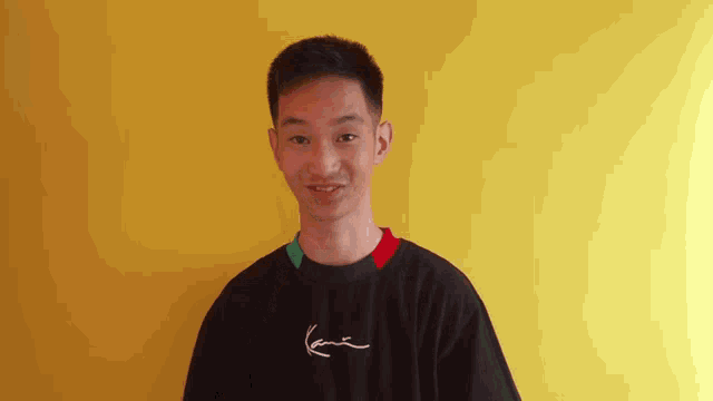 a young man wearing a black karl kani t-shirt