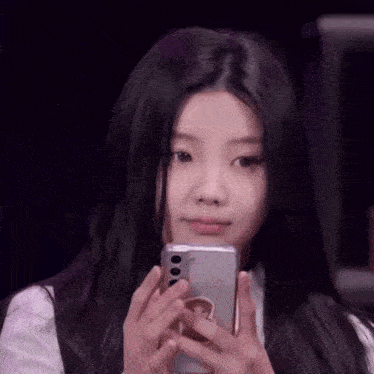 a young girl is holding a cell phone in her hands .