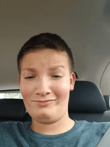 a boy in a blue shirt is making a funny face
