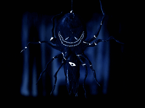 a spider with a face painted on it is hanging from a string