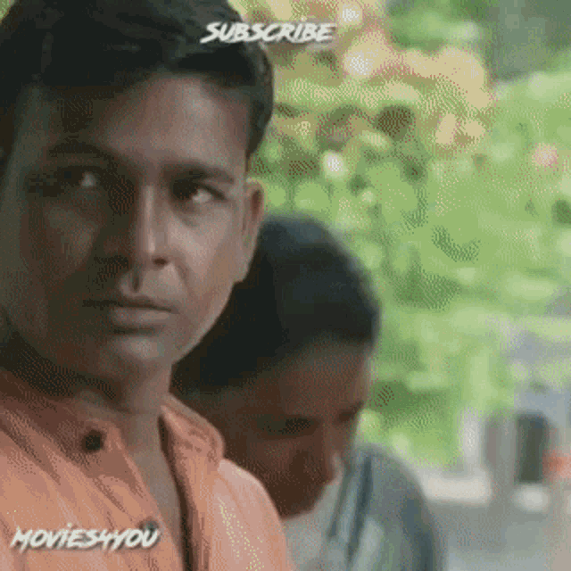 a man in an orange shirt is looking at the camera with the words subscribe on his head