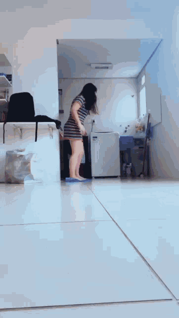 a woman in a striped dress is standing on a tile floor