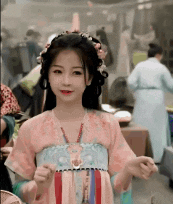 a woman in a pink dress with flowers in her hair is standing in front of a crowd .