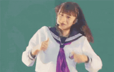 a girl in a sailor suit is giving a thumbs up .