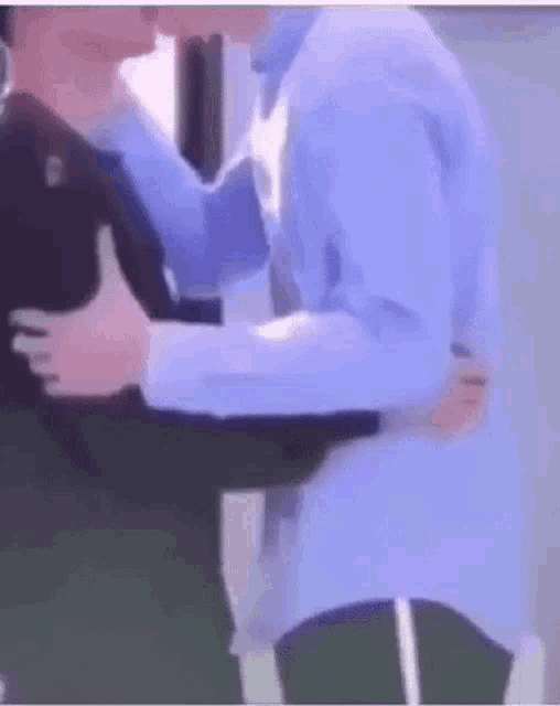 two men are hugging each other and kissing in a room .