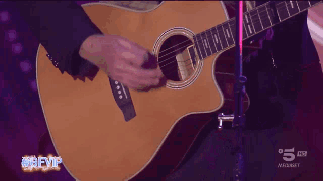 a man singing into a microphone while playing a guitar with the hashtag #gfvip