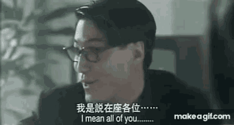 a man wearing glasses is sitting at a table and talking to another man in a foreign language .