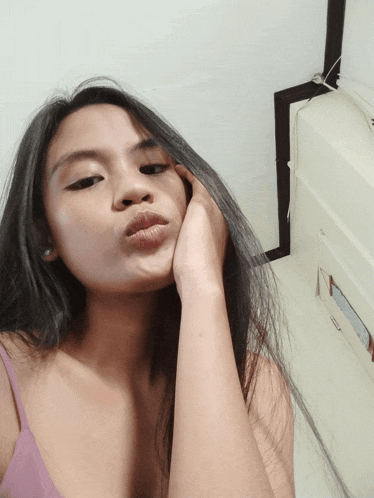a woman in a purple tank top takes a selfie