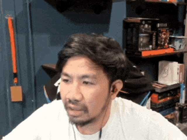 a man with a beard is wearing a white shirt and ear buds