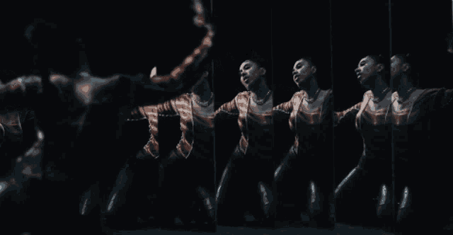 a woman is dancing in front of a mirror and her reflection is visible