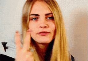 a close up of a woman 's face with a ring on her finger