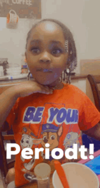 a little girl wearing an orange shirt that says be your period