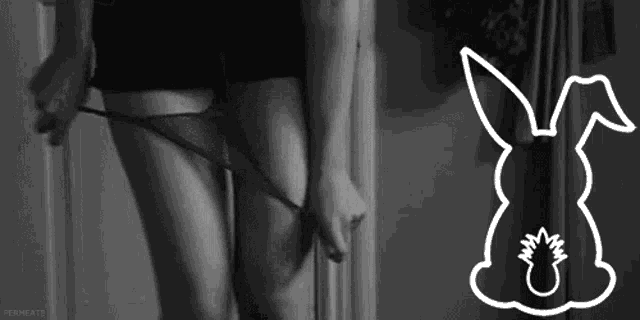 a woman is taking off her underwear in a black and white photo with a drawing of a rabbit .