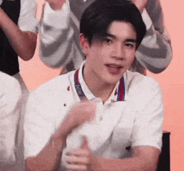a young man in a white shirt is giving a thumbs up sign .