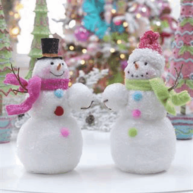 a couple of snowmen standing next to each other on a table .