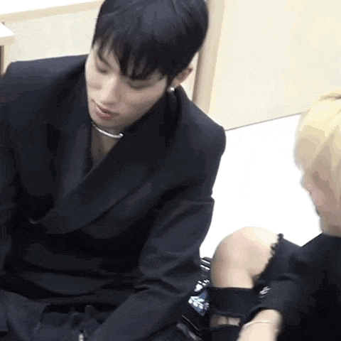 a man in a black suit is sitting next to another man in a black dress .