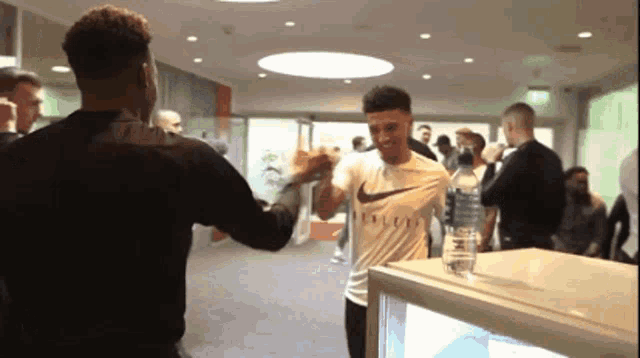 a man wearing a nike shirt is giving another man a fist bump