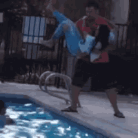 a man is carrying a woman over a pool