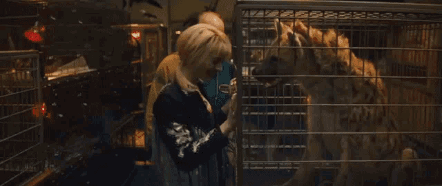 a man and a woman are standing in front of a cage with a tiger inside of it
