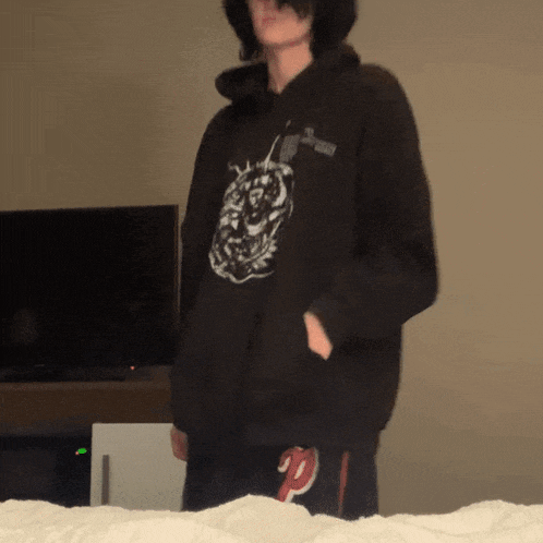 a person wearing a black hoodie with a picture of a lion on it