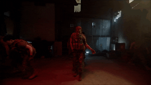a man in a military uniform is walking in a dark room with a sign that says exit