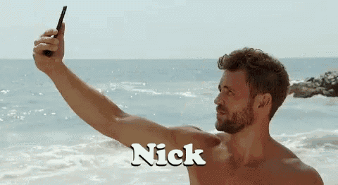 a shirtless man is taking a picture of himself on the beach .