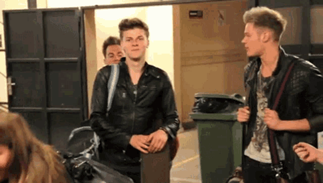 a group of young men in leather jackets are standing next to each other .