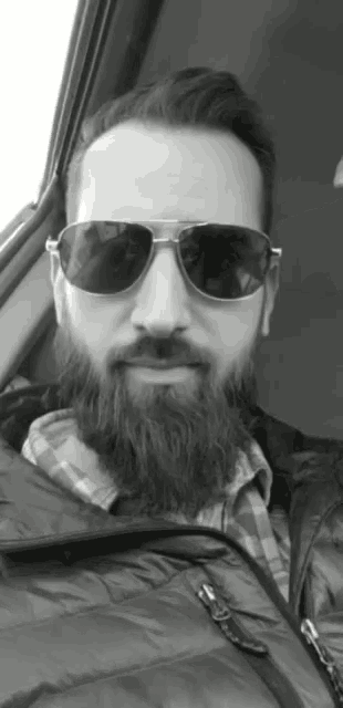 a man with a beard is wearing sunglasses and a jacket