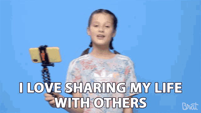 a young girl is holding a cell phone on a tripod and says i love sharing my life with others