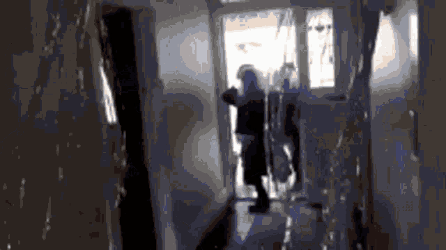a person is standing in a hallway looking out a door